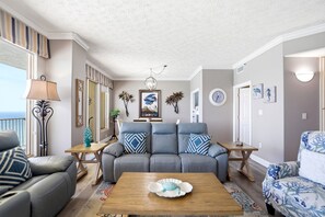 Ein Wohnzimmer mit grauem Sofa, einem Holztisch und Meerblick.