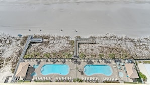 An aerial view of a beachside resort with two swimming pools, a boardwalk, and a beach area. - Gulf Crest 2304 | Your Gulf-Front Home Away From Home! (Panama City Beach)