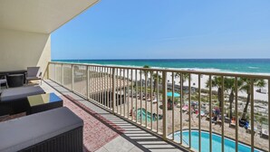 Ein Balkon mit Korbmöbeln, einem Pool und Blick auf den Strand.