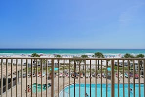 A pool area with a view of the beach and ocean.