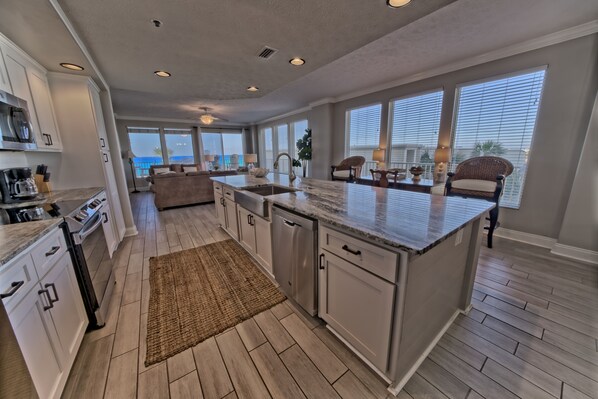 A spacious kitchen with a large island, white cabinetry, and a view to the outside.