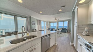 A modern kitchen with a large island, built-in appliances, and a view to the outside. - Gulf Crest 301 – 3BR Haven with 360° Views of PCB! (Panama City Beach)
