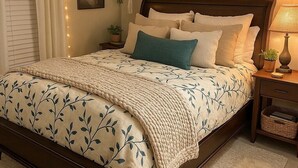 Un dormitorio con cama, mesitas de noche, una planta colgante y un adorno de tabla de surf en la pared.