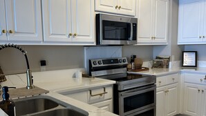 Una cocina con armarios blancos, electrodomésticos de acero inoxidable y encimera de mármol.