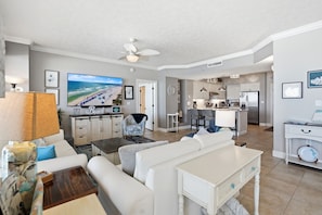 A living room with a TV, sofa, coffee table, and a dining area with chairs and a table. - Relax at Gulf Crest: 2-Bedroom Condo Bella! (Panama City Beach)