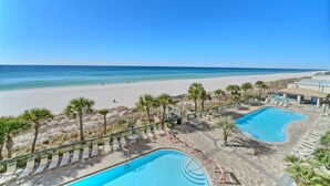 Un resort con piscina, playa y palmeras.