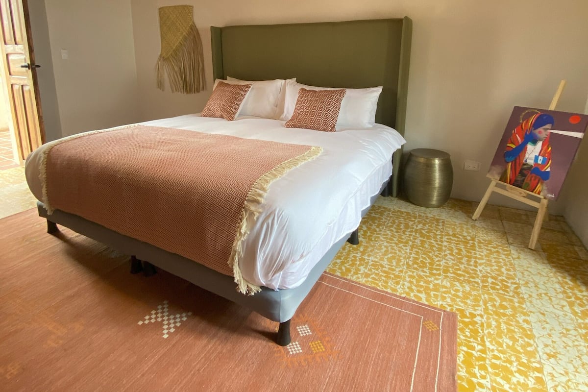 Un dormitorio con cama, techo de madera y un cuadro en la pared.