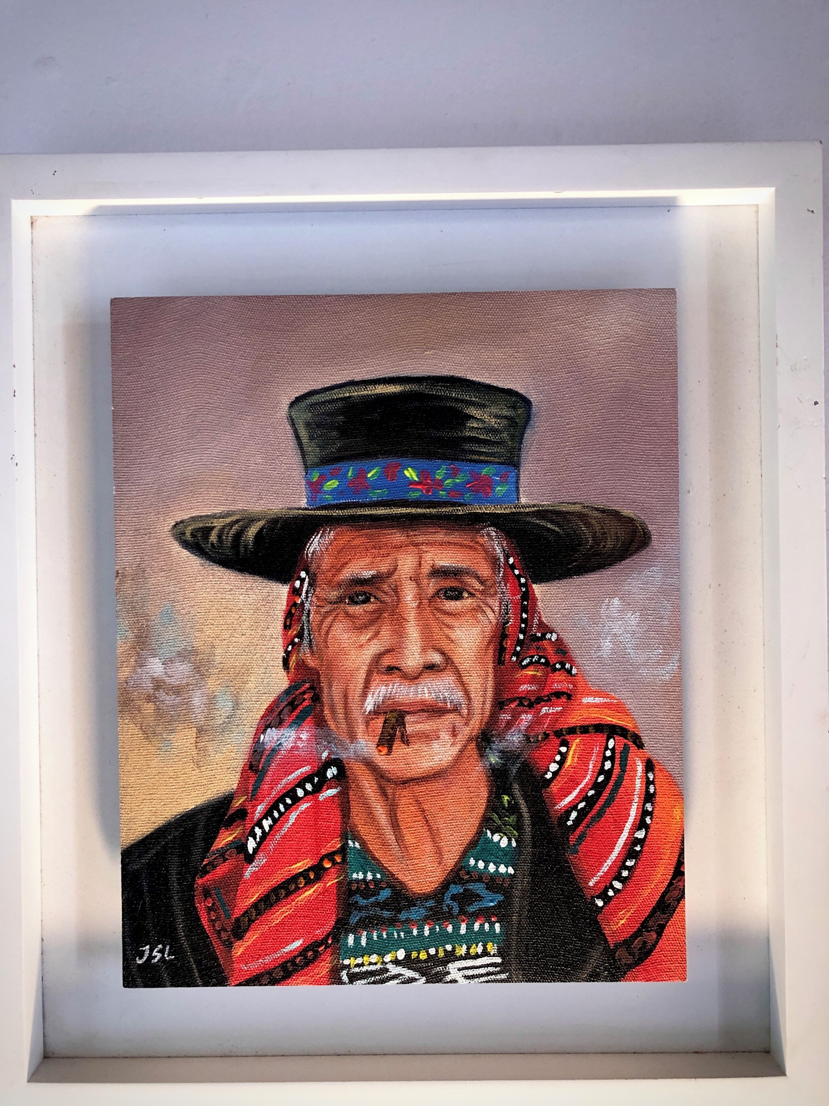 Un tableau encadré représentant une personne portant un chapeau et des vêtements à motifs.