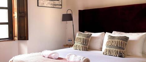 A neatly made bed with a patterned bedspread, two pillows, and a bedside lamp.