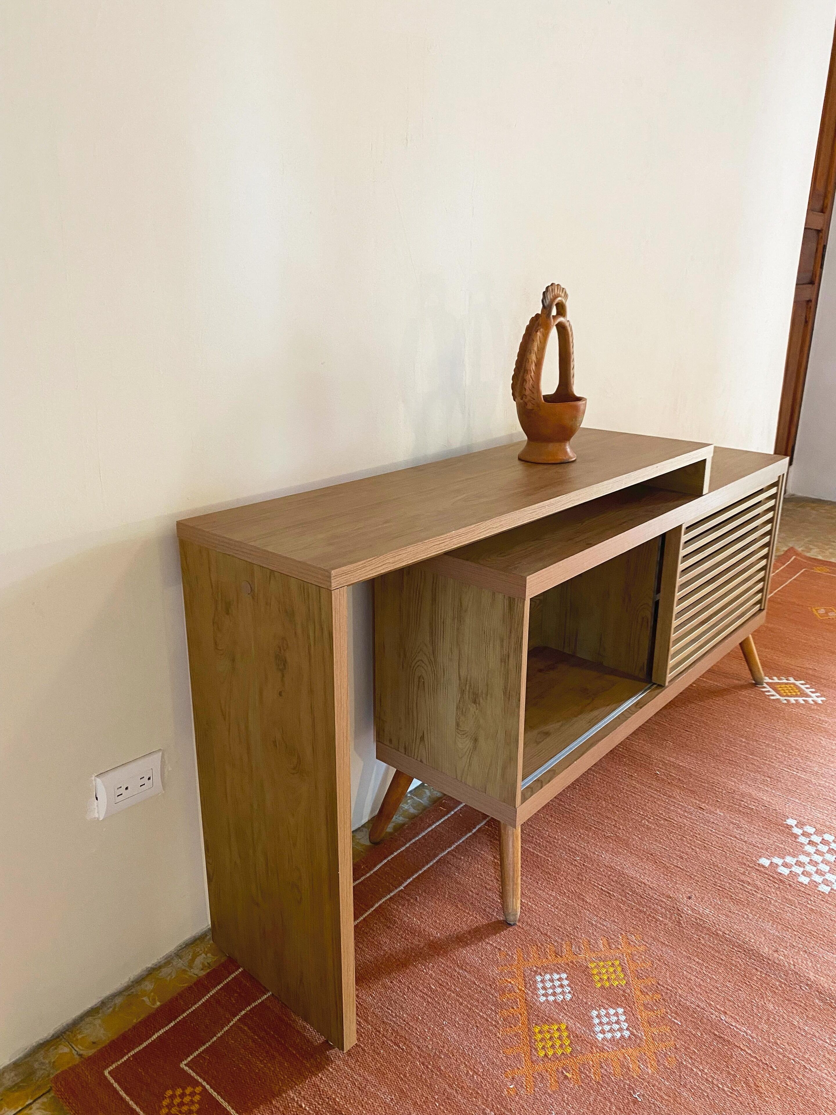 Un escritorio de madera con estante incorporado y un objeto decorativo encima.