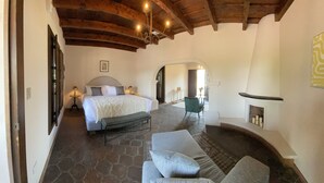 Un dormitorio con una cama grande, un banco, una chimenea y suelo de piedra.
