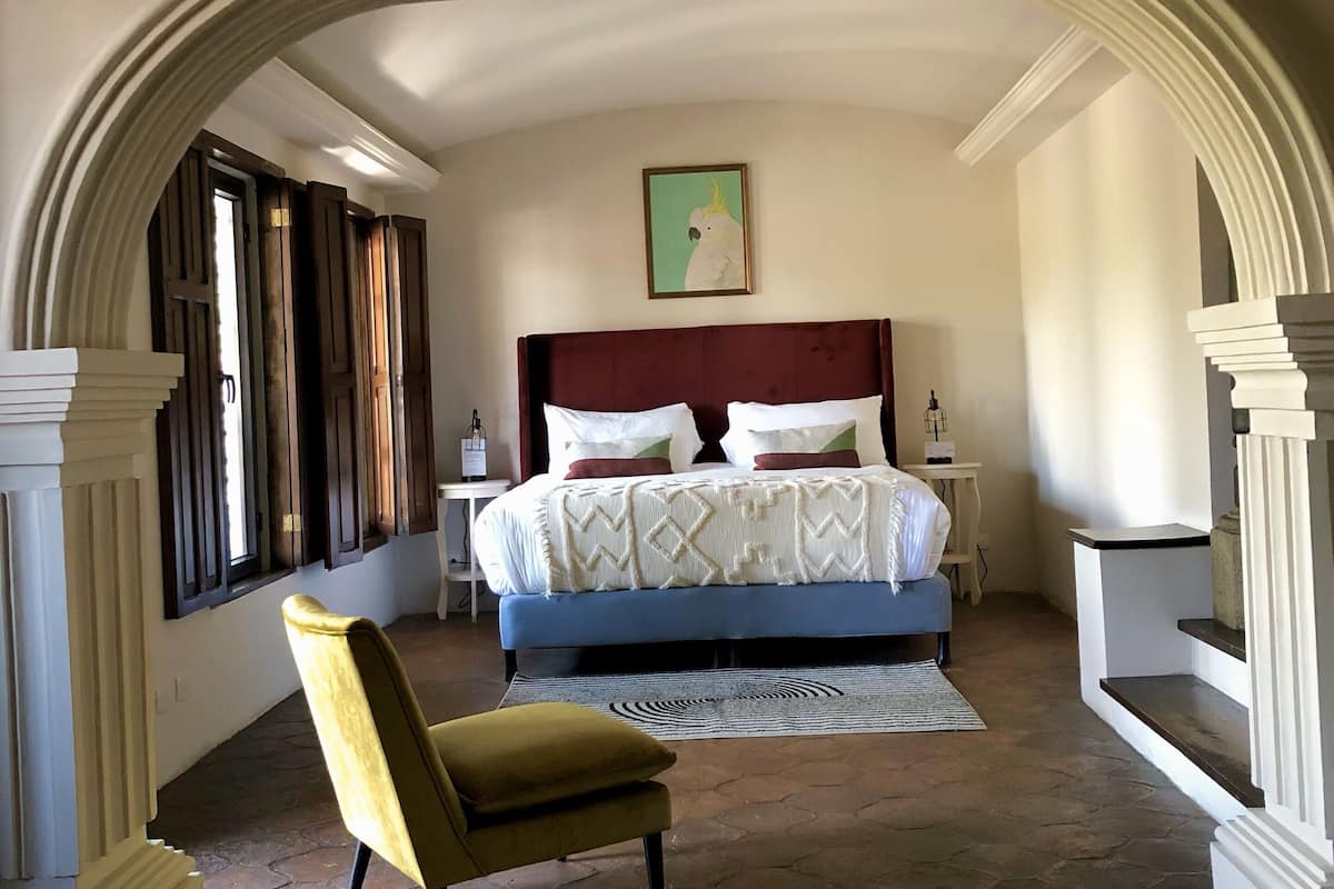 Un dormitorio con una cama grande, una silla y un cuadro en la pared.