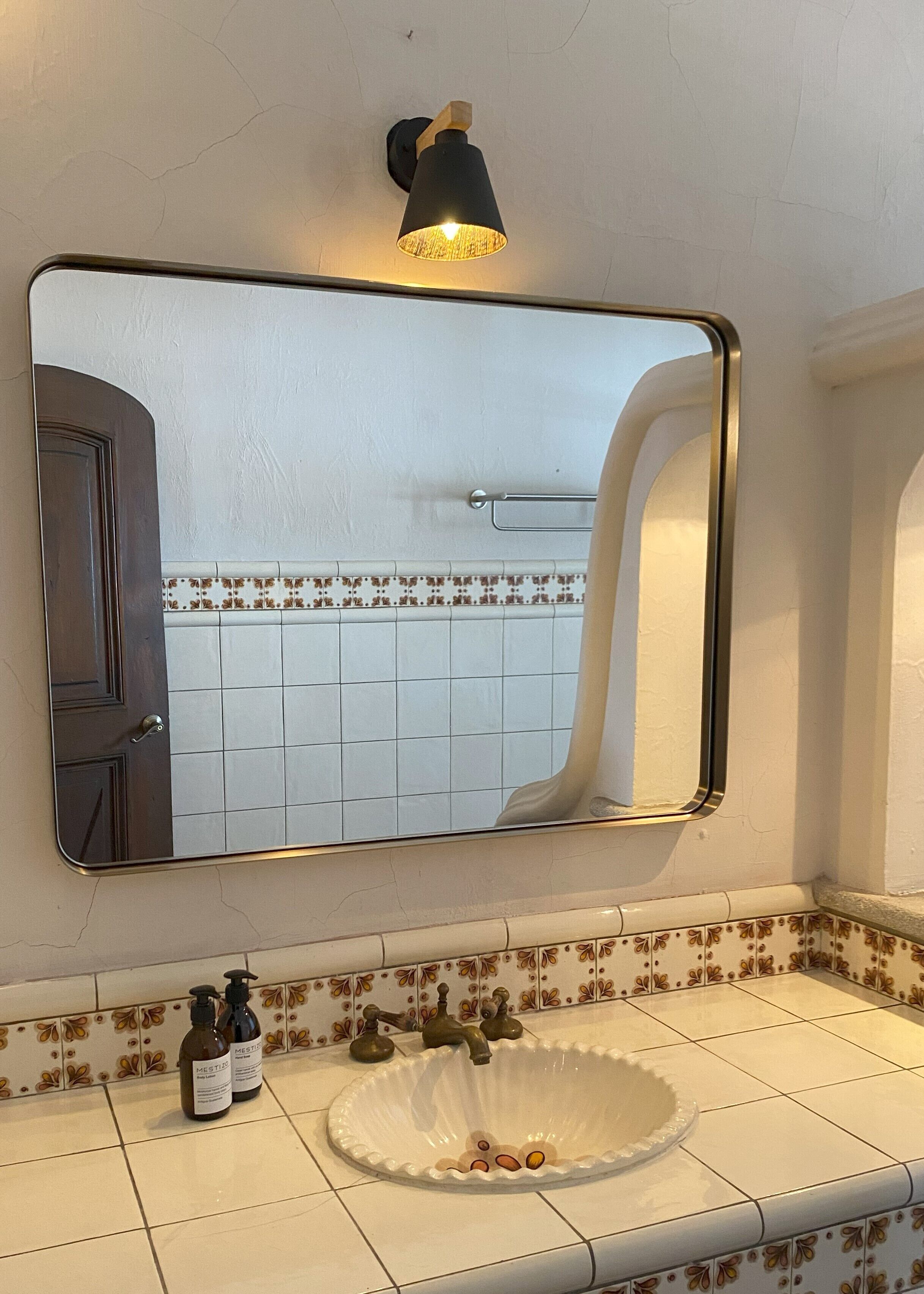 Un baño con un espejo grande, un lavamanos con una pila decorativa y dos botellas de jabón.
