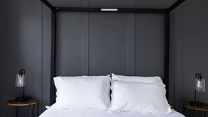 Un dormitorio moderno con una cama grande, paredes oscuras y dos mesitas de noche con lámparas.