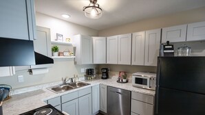 A modern kitchen with stainless steel appliances, white cabinets, and a marble countertop.