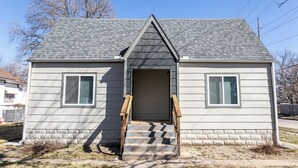 A two-story house with a front entrance, a small porch, and a visible garage door.