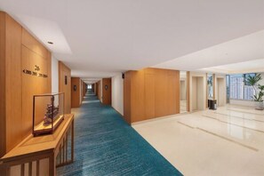 Un pasillo de hotel con paneles de madera, una alfombra azul y un suelo pulido.