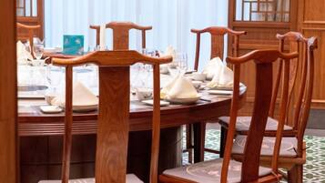 Una mesa de comedor lista con sillas, platos y vasos.