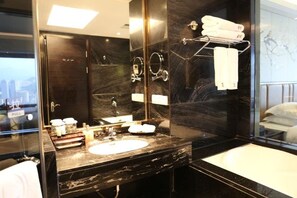 Un baño moderno con un espejo grande, un lavamanos y una bañera.