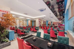 A modern restaurant with multiple dining areas, a central black table, and a staircase leading to an upper level. - Plum Garden International Hotel (Sanming)