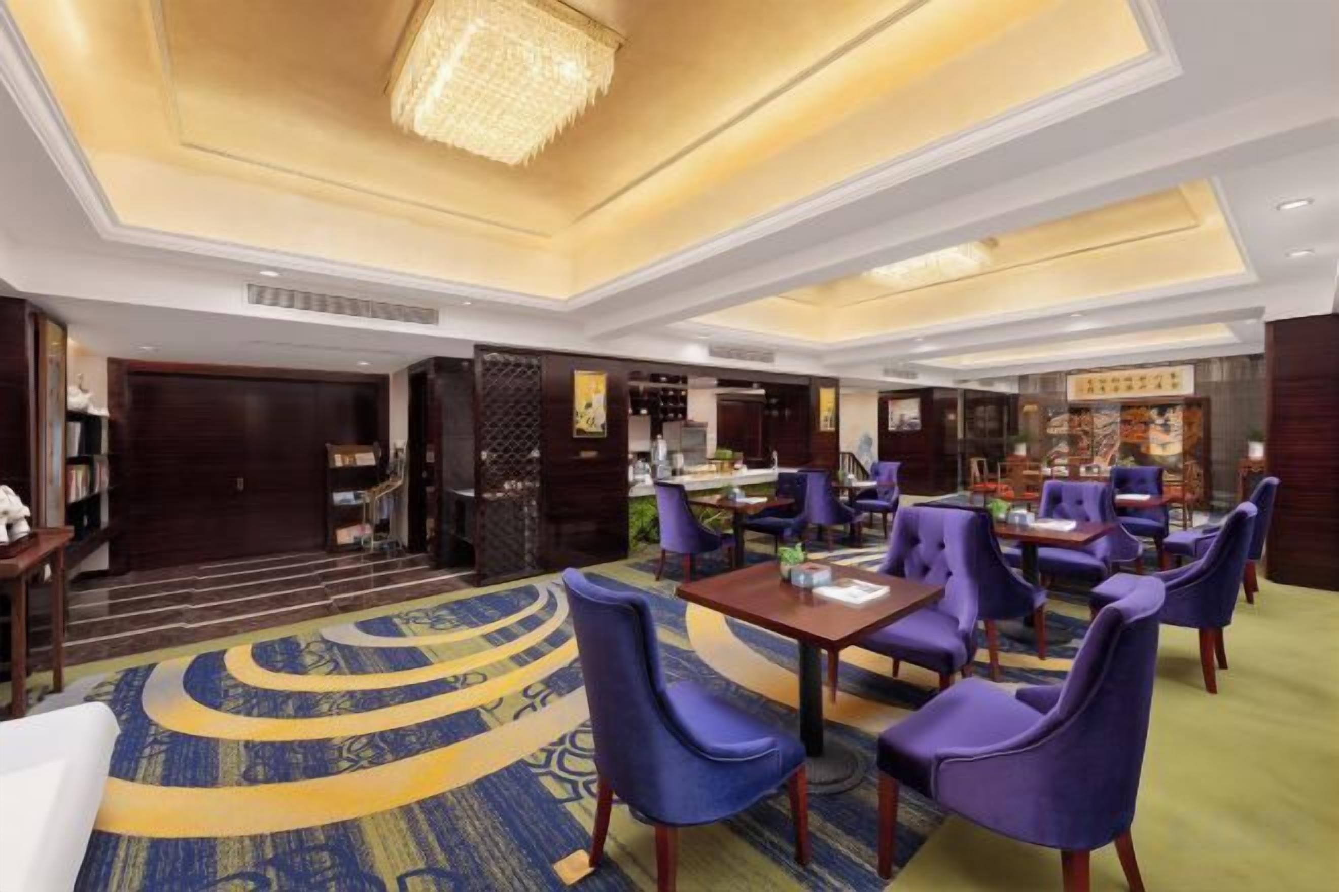 A hotel lobby with a reception desk, seating area, and a bar.