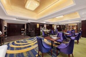 A hotel lobby with a reception desk, seating area, and a bar.