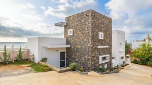 A modern building with a stone facade, a flat roof, and a small entrance.