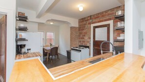 A kitchen with a brick wall, a gas stove, and a wooden countertop. - Modern Loft in Historic Birdtown - Unit 4 (Lakewood)
