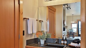 A bathroom with a wooden vanity, a mirror, a sink, and a potted plant. - Waterfront 1 bedroom condo - private deck offering spectacular views (Langley)