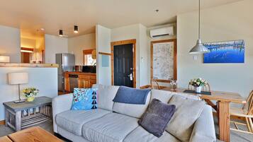 A living room with a sofa, a wooden coffee table, a dining table with chairs, a lamp, and a map on the wall.