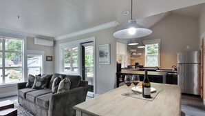 Una cocina moderna con comedor, ventanas amplias y un sofá gris.