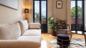 A modern living room with a beige sofa, a small round table, and a potted plant. - Elegant Duplex Apt in Downtown by Lisbeyond (Porto)