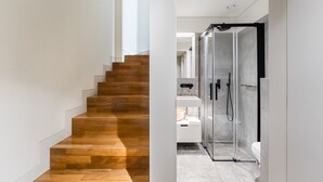 A modern staircase leading to a bathroom with a glass shower enclosure. - Elegant Duplex Apt in Downtown by Lisbeyond (Porto)
