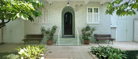 A courtyard with a tiled floor, two benches, and potted plants.