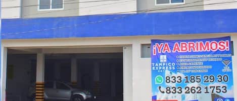Un hotel llamado Tampico Express con un cartel que anuncia servicios como WiFi, aire acondicionado y recepción las 24 horas.