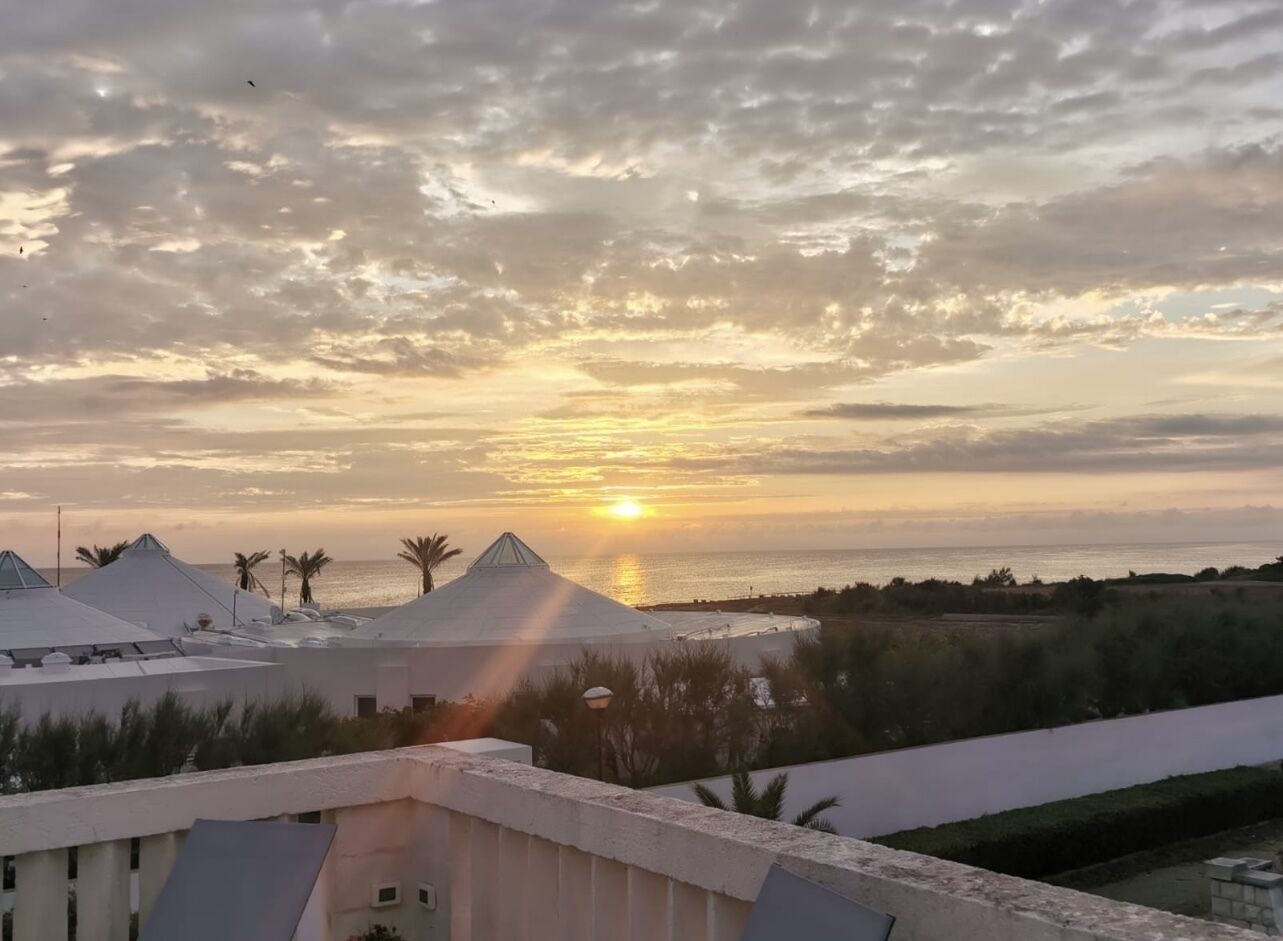 Tramonto sulla costa, con edifici moderni e palme.