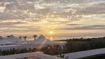 Tramonto sulla costa, con edifici moderni e palme.