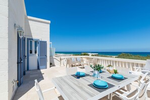 Une terrasse avec une table dressée pour le dîner, offrant une vue sur la côte.