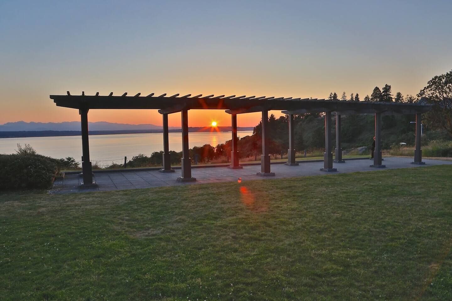 A gazebo with a view of the sunset over a body of water.