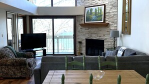 A living room with a fireplace, a television, and a dining area with a table and chairs.