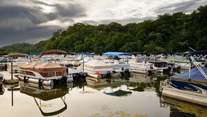 A marina with various boats docked, surrounded by lush greenery.