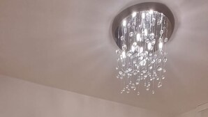 Een slaapkamer met een groot bed, een wereldkaart aan de muur, een klein nachtkastje met een lamp en een kroonluchter.