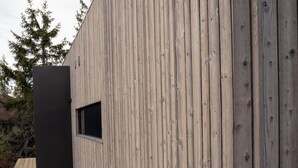 A modern building with vertical wooden siding and a wooden deck. - Grend Blefjell (Flesberg)