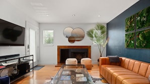 Una sala de estar moderna con chimenea, sofá de cuero y una mesa de centro con revistas.