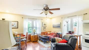 Cozy living room with a leather sofa, wooden side table, and woven stool, perfect for relaxing and dining.