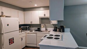 A compact kitchen with white cabinets, a microwave, a dishwasher, and a stove.