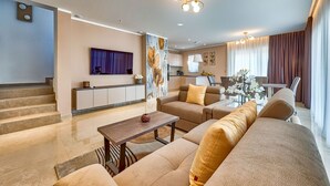 A modern living room with a sofa set, a coffee table, and a TV mounted on the wall.