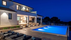 A modern pool area with lounge chairs and a well-lit outdoor space.