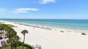 Ein Strand mit weißem Sand, klarem, blauem Wasser und einer Reihe blauer Sonnenschirme.