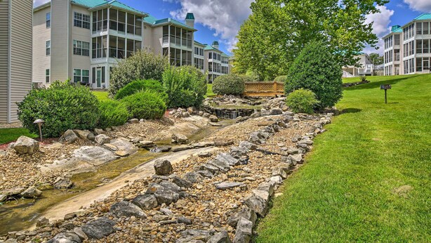 Un quartiere residenziale con un piccolo corso d'acqua, vegetazione rigogliosa e palazzi a più piani con balconi.